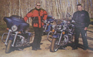 Jeff Keay leans against blue Harley with a friend nearby