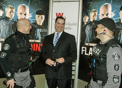 Hugh Dillon and Enrico Colantoni, in SWAT-like uniforms, flank James Moore, in a suit